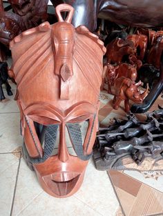 a wooden mask sitting on top of a tiled floor next to other figurines