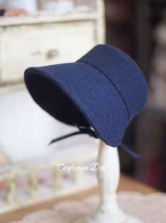 a blue hat sitting on top of a white mannequin's head in front of a dresser