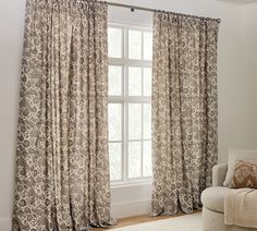 a living room with a couch, chair and window covered in curtained drapes