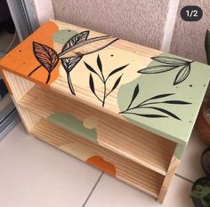 a wooden box sitting on top of a tile floor next to a potted plant