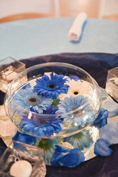 a glass bowl filled with blue flowers on top of a table