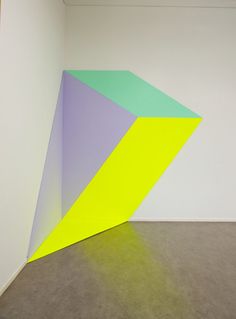 an abstract painting in a white room with yellow and purple shapes on the wall,