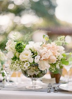 a table topped with lots of white and green flowers