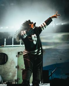 a man standing on top of a stage with his hand up in the air while holding a microphone