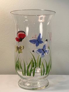 a glass vase with butterflies painted on it