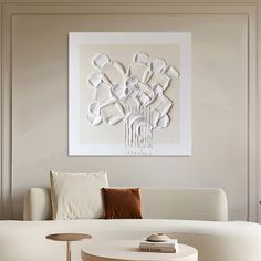 a living room with white furniture and art on the wall above the coffee table in front of the couch