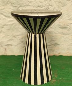 a black and white striped table sitting on top of a green floor next to a wall