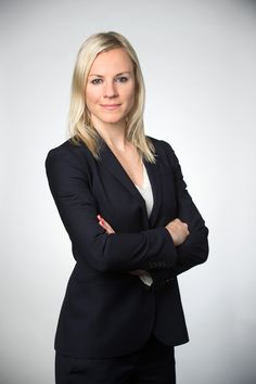 a woman in a business suit posing for a photo with her arms crossed and looking at the camera