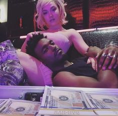 a woman laying on top of a bed next to a man with money in his lap