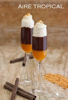 two wine glasses filled with liquid and topped with whipped cream, cinnamon sticks and anise