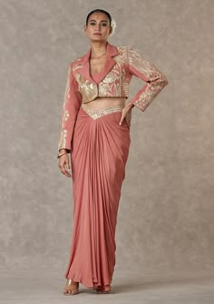 Introducing a cropped blazer, featuring intricate embroidery with moti, dori, and sitara kaam. The blazer includes full sleeves, a notch collar, and a center front closure for a polished look. Paired with a drape skirt adorned with a 'V' shaped waist belt embroidered with dori & sitara kaam, the ensemble is completed by a salmon fitted tube with a center back closure and detachable strap, offering a blend of sophistication and modern flair. Cropped Blazer And Skirt, House Of Masaba, Caribbean Fashion, Blazer And Skirt Set, Draping Fashion, Draped Skirt, Women Skirt, Blazer And Skirt, Lakme Fashion Week