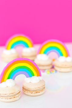 rainbow cookies with white frosting and sprinkles are on a pink background