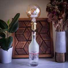 a glass bottle sitting on top of a table next to a vase with flowers in it