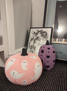 three decorative pumpkins sitting on top of a carpeted floor next to a framed photo