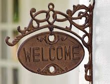 a welcome sign hanging from the side of a building with an ornate design on it