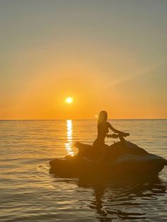 a woman riding on the back of a jet ski in the middle of the ocean