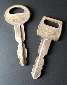 two old keys are sitting next to each other on a black surface with the words ford written on them