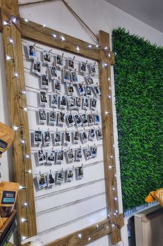 a green wall with pictures hanging on it and string lights strung from the sides around it