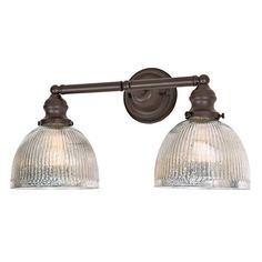 two light bathroom fixture in an antique bronze finish with clear glass shades on the bulbs