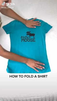 a woman holding onto a t - shirt with the words how to fold a shirt on it