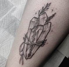 a black and white tattoo on the leg of a woman with an arrow in it