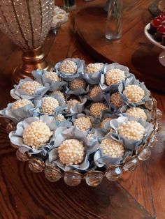 a glass bowl filled with white flowers on top of a wooden table