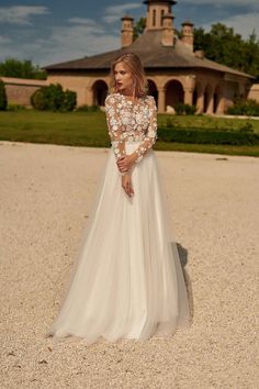 a woman in a wedding dress is standing on the gravel outside an old building with a clock tower