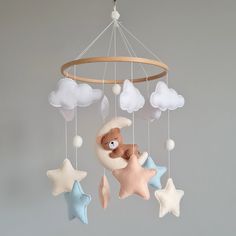 a crib mobile with stars, clouds and a teddy bear hanging from it's side