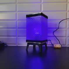 a purple lamp sitting on top of a wooden table next to a phone charger