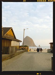 people are walking on the beach near houses