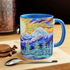 a blue coffee mug sitting on top of a wooden cutting board next to a cookie