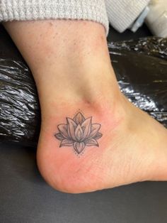 a small tattoo on the foot of a woman with a lotus flower in her center