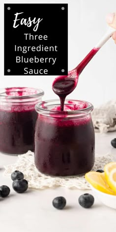 blueberry sauce in two jars with a spoon and lemon wedges on the side