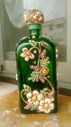 a green glass bottle with flowers on it