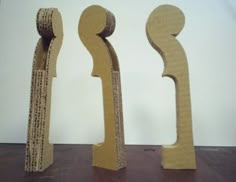 three cardboard sculptures made to look like letters