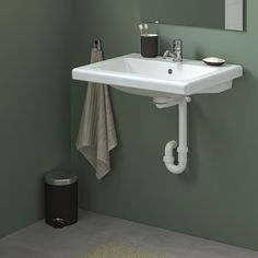 a white sink sitting under a bathroom mirror next to a trash can and towel dispenser