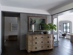 a living room with a large painting on the wall next to a chest of drawers