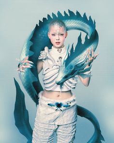 a woman with white hair and makeup holding a blue dragon statue in front of her face