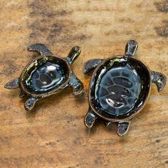 two small turtle figurines sitting on top of a wooden table