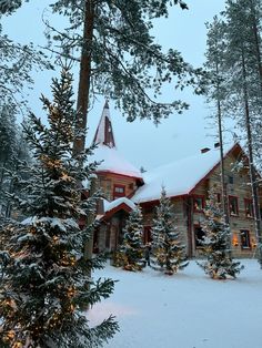 a log house surrounded by trees in the snow with lights on it's roof