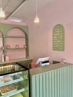 the interior of a bakery with pink walls and green counter tops, along with an ice cream display case