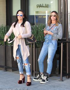 two women standing next to each other on the sidewalk