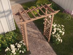 a small wooden arbor in the middle of a yard with white flowers and greenery