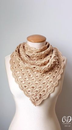 a white mannequin wearing a beige crochet scarf on top of a dummy