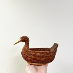 a hand holding a wicker basket shaped like a duck