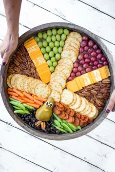 a platter filled with crackers, grapes, olives, cheese and fruit