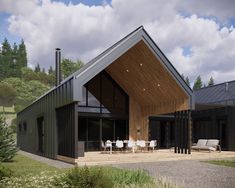 a modern house with an outdoor patio and dining area in the foreground, surrounded by greenery