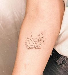 a person with a tattoo on their arm holding a book in one hand and an open book in the other