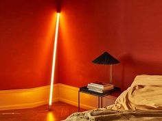 a lamp that is on top of a table next to a bed with red walls