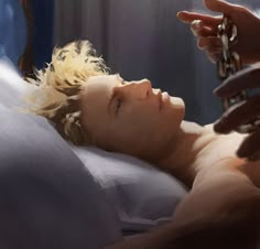 a man laying in bed with his hand on the chain